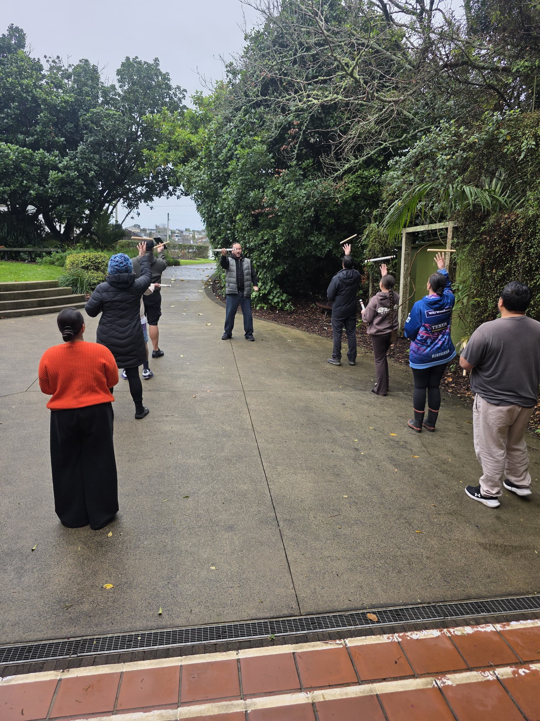 Kaihaka Kapa Haka whānau practising tītī tōrea outside at Ō Wairoa Marae